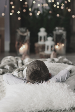 Boy with hands behind head lying on floorの写真素材