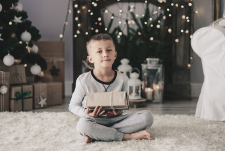 Boy with christmas present sitting on rugの写真素材