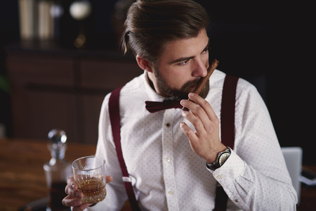 Businessman with glass of whiskey and cuban cigar at office の写真素材