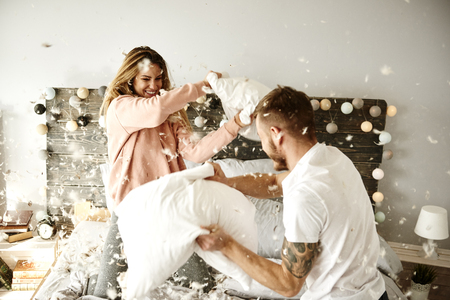 Couple having a fun while pillow fightの写真素材
