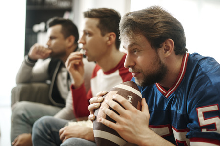 Focused watching football game at home の写真素材