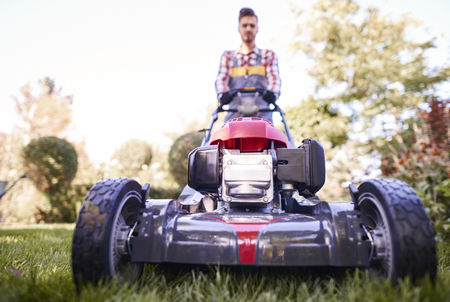 Defocused gardener pushing modern mower