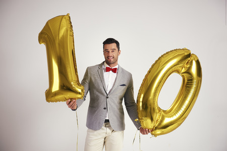 Young man with golden balloon building the figure 10