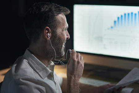 Side view of man listening to music in his officeの写真素材