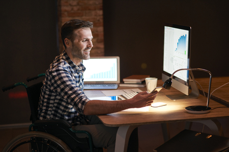 Disabled man working with technology at nightの写真素材