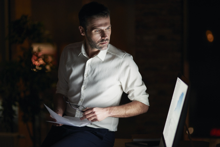 Serious man analyzing document in his officeの写真素材
