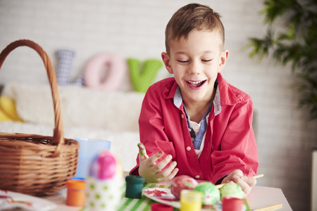 Happy boy painting eggs for Easter