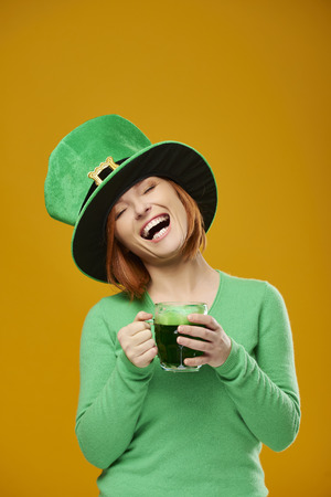 Happy woman with leprechaun's hat drinking beerの写真素材