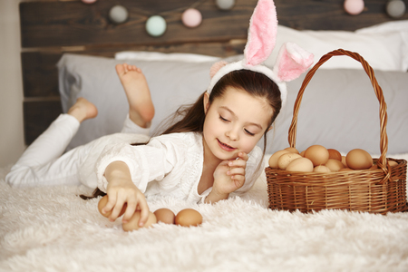 Happy child playing with eggs in bedroomの写真素材