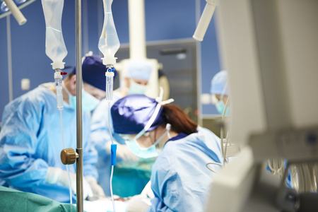 Intravenous drip and busy surgeons in the backgroundの写真素材
