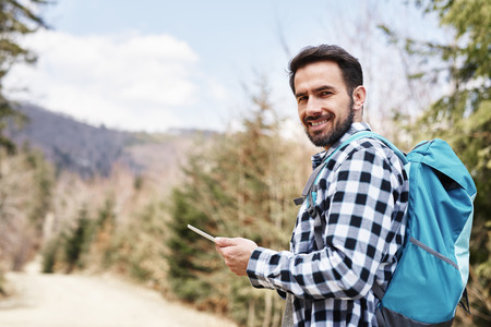 Portrait of smiling hiker using mobile phone during hiking trip 