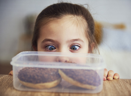 Child looking at delicious donutsの写真素材