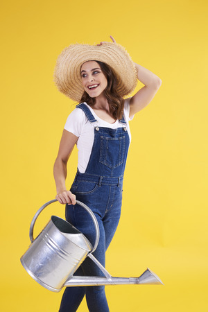 Beautiful woman with watering can in studio shotの写真素材