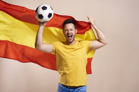 Screaming Spanish fan holding flag and soccer ballの写真素材