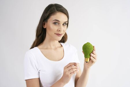 Front view of woman holding a energy efficient light bulb