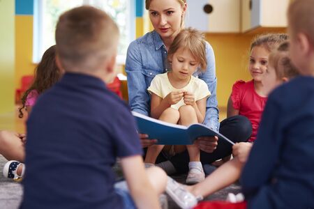 Teacher and children reading a book in the preschoolの写真素材