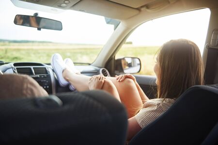Woman holding her legs on dashboard in car