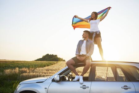 Young couple with rainbow flag enjoying the viewの写真素材
