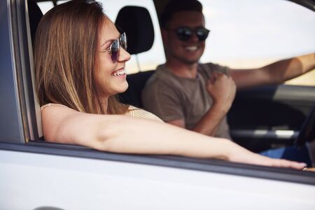 Happy woman traveling by car as passenger in summertime