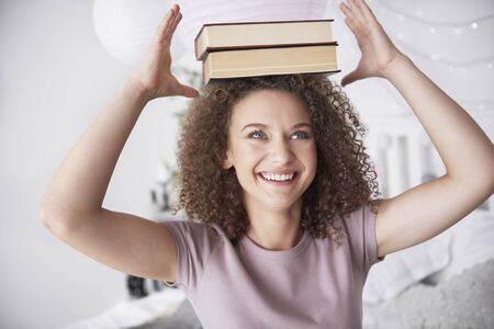Teenage girl with books on her head