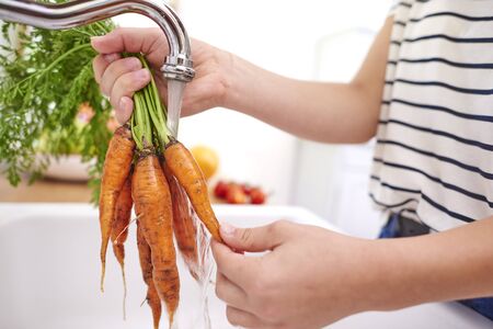Woman washing fresh and organic carrotsの写真素材