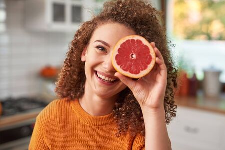 Portrait of woman covering her eye with grapefruitの写真素材