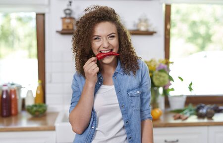 Young woman holding red pepper in her mouthの写真素材