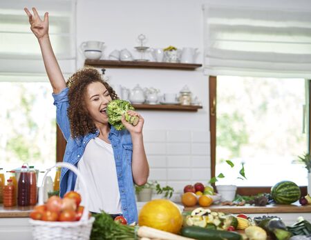 Happy woman singing while cooking a mealの写真素材