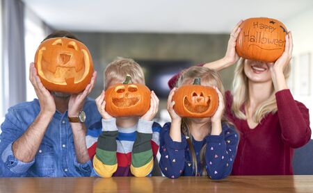 Family holding halloween pumpkins in front of their face の写真素材