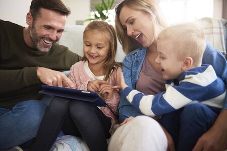 Family with tablet spending time together in living room 