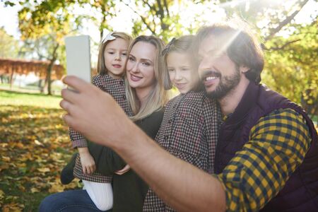 Happy family making a selfie in autumn forestの写真素材