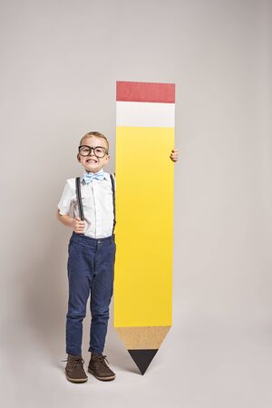 Smiling boy holding a big pencil の写真素材
