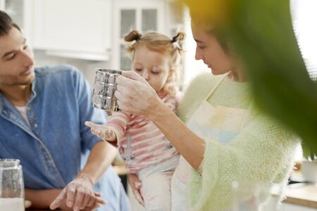 Parents teaching daughter how to bake