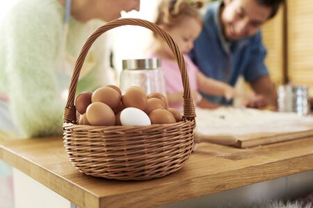 A full basket of eggs and family in the background 