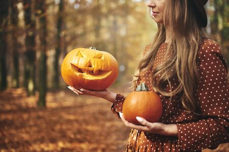 Woman holding halloween pumpkin in autumn forestの写真素材