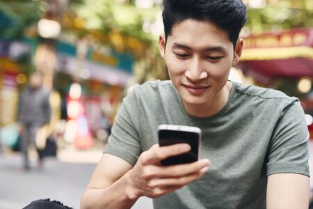 Young Vietnamese man using mobile phone in the city
