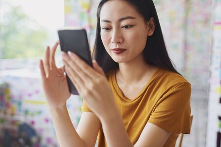 Beautiful Vietnamese woman looking at mobile phoneの写真素材