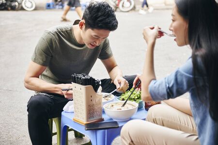 Young couple trying to vietnamese food in the city streetの写真素材