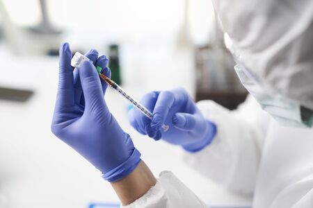 Human hands holding coronavirus medicine and a syringe