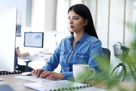 Asian woman typing on computer keyboard