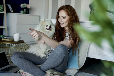 Redhead woman with a dog in the living roomの写真素材