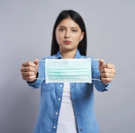 Asian woman holding a protective mask in handsの写真素材