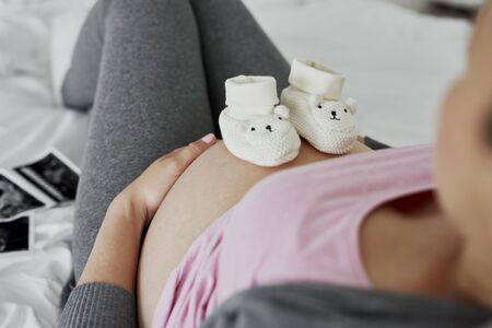 Baby shoes on pregnant abdomenの写真素材