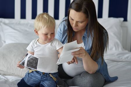 Pregnant woman browsing ultrasound images with her offspring