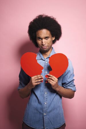 Sad African man with a broken heart in studio shot.の写真素材