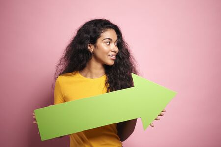 Smiling African woman holding arrow in a studio shot.