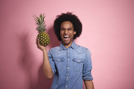 Happiness African man holding a pineapple in a studio shot.の写真素材