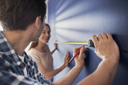 Couple taking measure on the blue wallの写真素材
