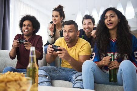 Group of friends spending time at home playing on the console
