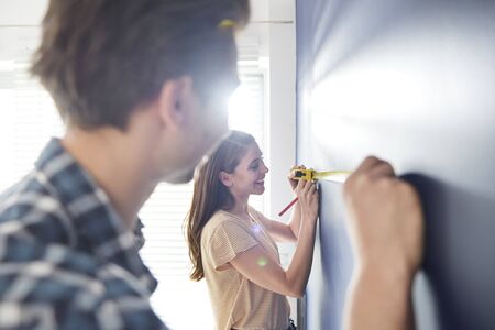 Cooperating couple using measure tape on the wallの写真素材